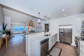 A modern kitchen with a large island, stainless steel appliances, and a view to the outside.