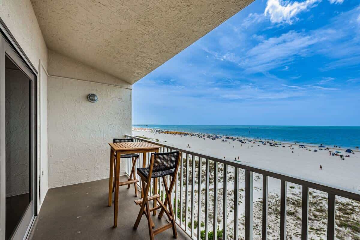 Ein Balkon mit Blick auf einen Strand, einem Tisch und zwei Stühlen.