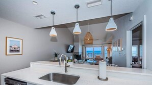 A modern kitchen with a large island, stainless steel sink, and pendant lighting. - A17 Villas of Clearwater Beach Gulf-Front Condo (Clearwater Beach)