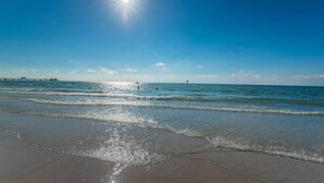 A beach with clear skies, calm water, and a pier in the distance. - A17 Villas of Clearwater Beach Gulf-Front Condo (Clearwater Beach)