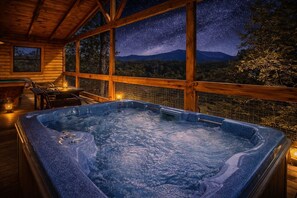 A hot tub with a wooden deck and a night sky view.