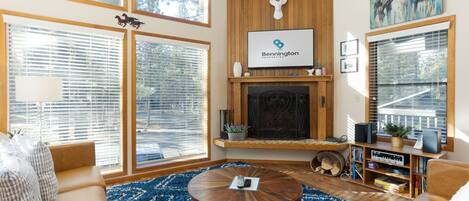 A spacious living room with a fireplace, large windows, a mounted deer head, and a mounted horse sculpture.
