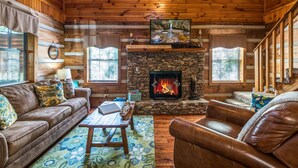 A cozy log cabin interior with a stone fireplace, leather furniture, and wooden walls. - ER17 - The Perfect Getaway | Great location - Close to town! (Pigeon Forge)