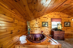 A wooden cabin bathroom with a wooden bathtub, a vanity with a mirror, and framed pictures on the wall. - ER17 - The Perfect Getaway | Great location - Close to town! (Pigeon Forge)