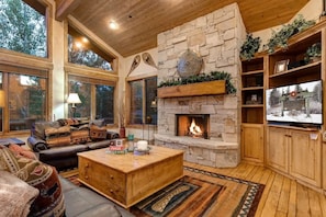 A cozy living room with a stone fireplace, leather furniture, and large windows. - Abode at Arrowood, 3 private master suites, hot tub, Deer Valley (Park City)