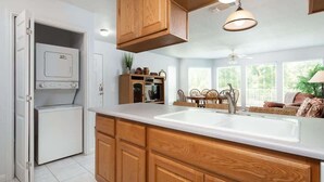 A kitchen with wooden cabinets, a built-in oven, a sink, and a dining area with chairs. - WW C301 Urban Bungalow (New Braunfels)
