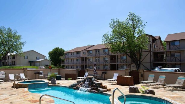 A hotel with a swimming pool, lounge chairs, and a waterfall feature. - WW C301 Urban Bungalow (New Braunfels)