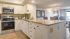 A modern kitchen with white cabinetry, stainless steel appliances, and a granite countertop. - Ocean One 315 - Oceanfront 3rd Floor Condo (Hilton Head Island)