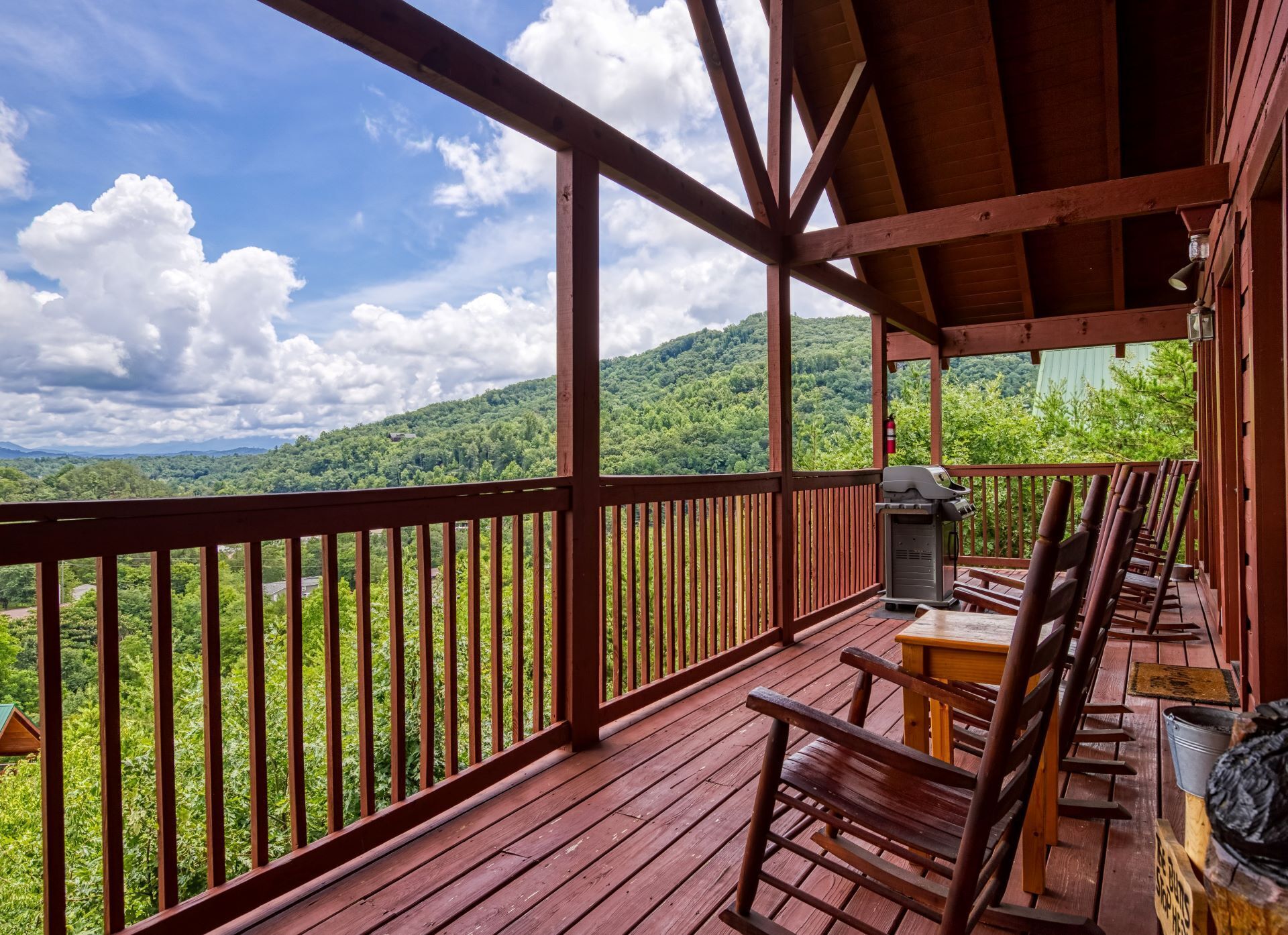 Eine Holzterrasse mit Tisch und Stühlen, mit Blick auf eine üppige grüne Landschaft.