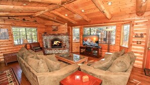 A log cabin interior with a stone fireplace, a television, and a sofa. - Columbine Oak Retreat- Log Style Cabin W/ Spa (Big Bear City)