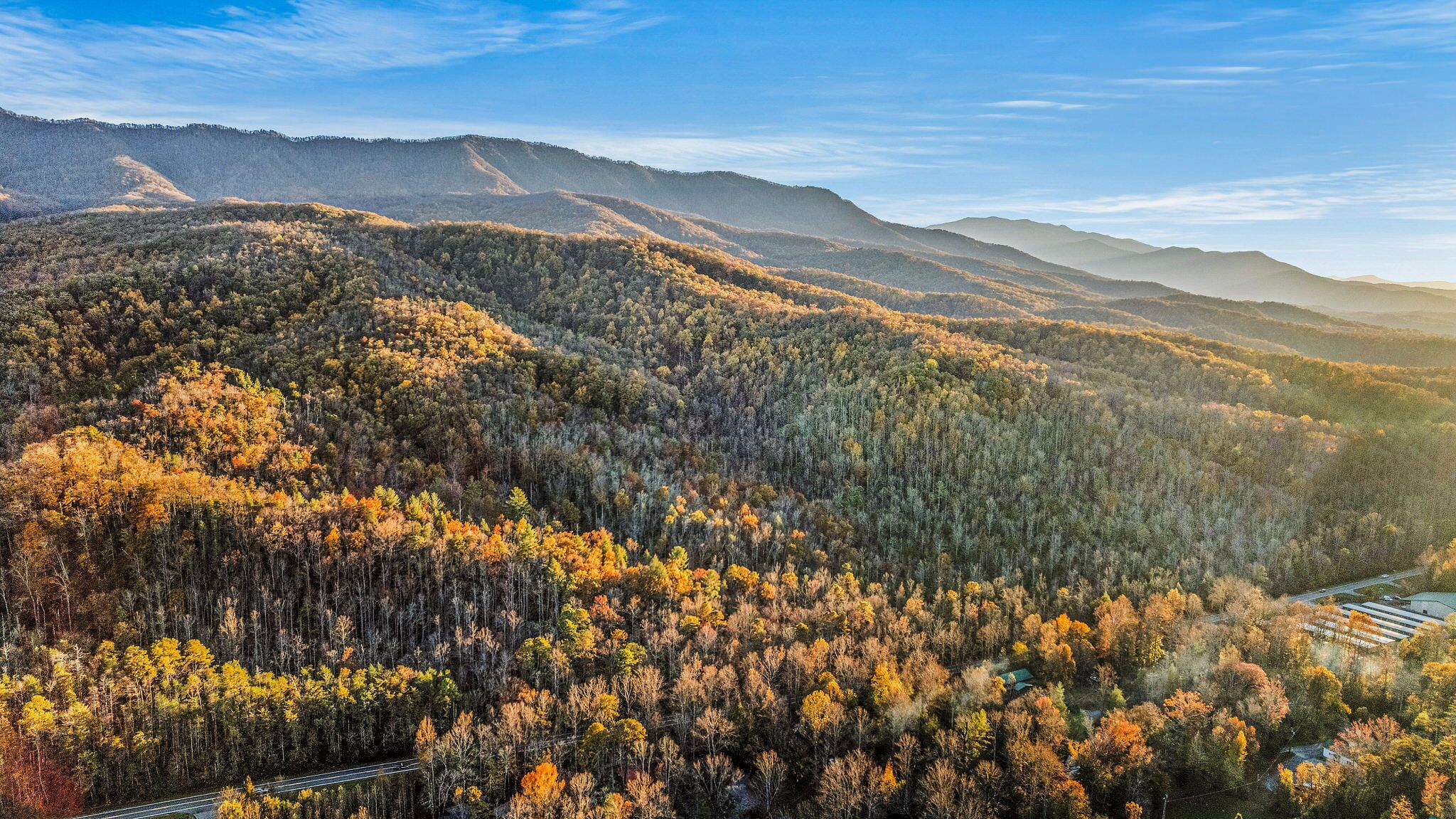 Een bergachtig landschap met dichte bossen en een weg die erdoorheen loopt.