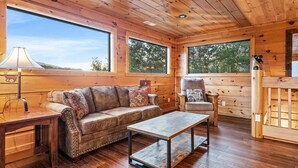 A wooden cabin interior with a leather sofa, a coffee table, and a lamp. - Take My Breath Away: Mountain Views, Theater (Gatlinburg)