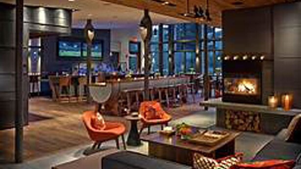 A modern living room with a fireplace, comfortable seating, and a bar area in the background. - Topnotch Resort, Stowe. Luxury 2/2 Resort Home just steps from the Spa.  (Stowe)