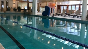 An indoor swimming pool with clear lane dividers, a blue slide, and lounge chairs around the pool area. - Topnotch Resort, Stowe. Luxury 2/2 Resort Home just steps from the Spa.  (Stowe)