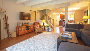 A spacious living room with a staircase, wooden furniture, a flat-screen TV, and a cozy seating area. - Topnotch Resort, Stowe. Luxury 2/2 Resort Home just steps from the Spa.  (Stowe)