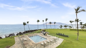 A pool area with lounge chairs and a view of the ocean. - Oceanfront Retreat | Split A/C | Pool | Walk to Beach & Dining (KIHEI)