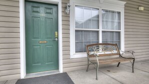 A green door with a number plate, a bench, and a window with blinds. - Colonial Crest 107 - Great location! - You can walk to town! (Pigeon Forge)