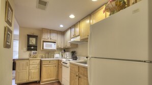 A kitchen with wooden cabinets, a white refrigerator, a microwave, and a dishwasher. - Colonial Crest 107 - Great location! - You can walk to town! (Pigeon Forge)