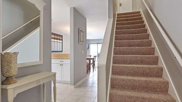 Un escalier menant à une salle à manger offrant une vue sur l’extérieur.