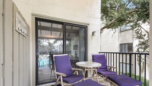 Un balcon avec deux fauteuils violets dotés de coussins et une petite table ronde.
