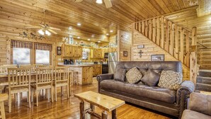 Un interior de madera con zona de comedor, un sofá y una escalera.