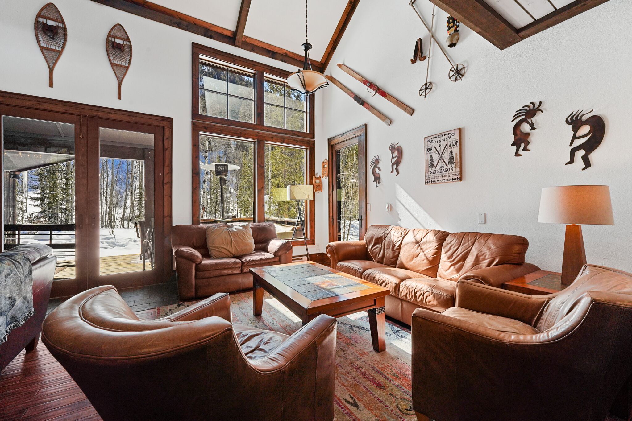 Una sala de estar acogedora con sofás de cuero, una mesita de centro y ventanas amplias que ofrecen vistas al exterior.