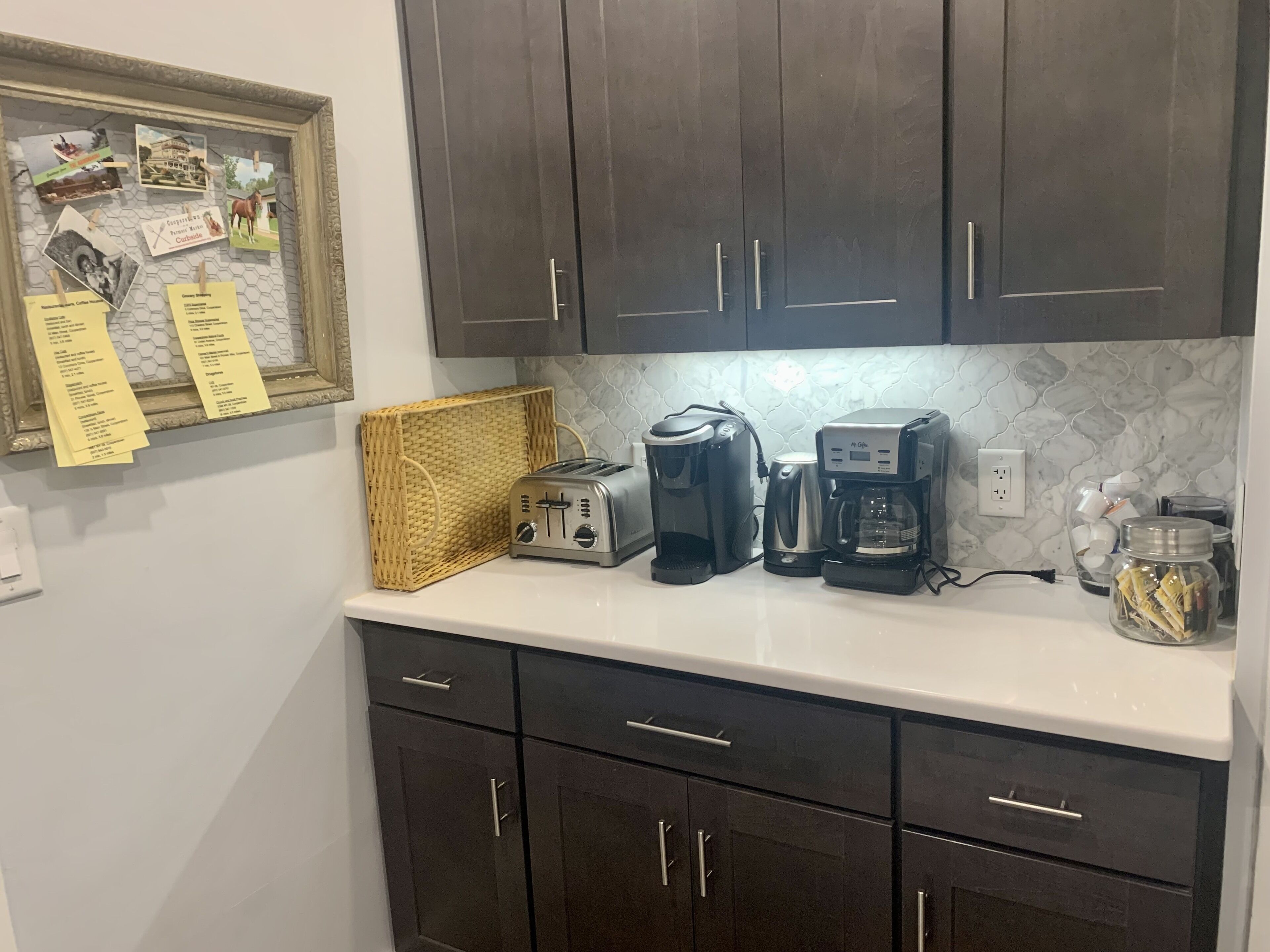 A kitchen with dark cabinets, a toaster, a coffee maker, and a basket.