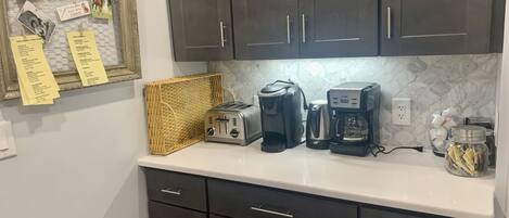 A kitchen with dark cabinets, a toaster, a coffee maker, and a basket.