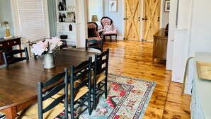 Un coin repas avec une table et des chaises en bois, un lustre et un tapis à motifs.