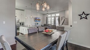 Una cocina moderna con armarios blancos, una mesa de comedor con sillas y un frutero.