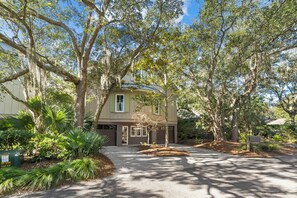 A two-story house with a covered porch, surrounded by mature trees and well-maintained landscaping.
