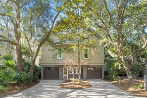 A two-story house with a driveway, surrounded by trees and shrubs. - Perfect Kiawah house! New construction, steps to beach w/pool, gorgeous decor (Kiawah Island)