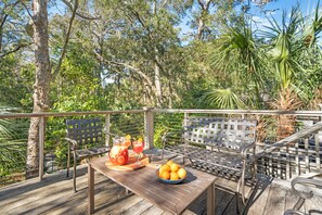 A wooden deck with a table, two metal chairs, a bowl of oranges, and a tray with fruit and drinks. - Perfect Kiawah house! New construction, steps to beach w/pool, gorgeous decor (Kiawah Island)