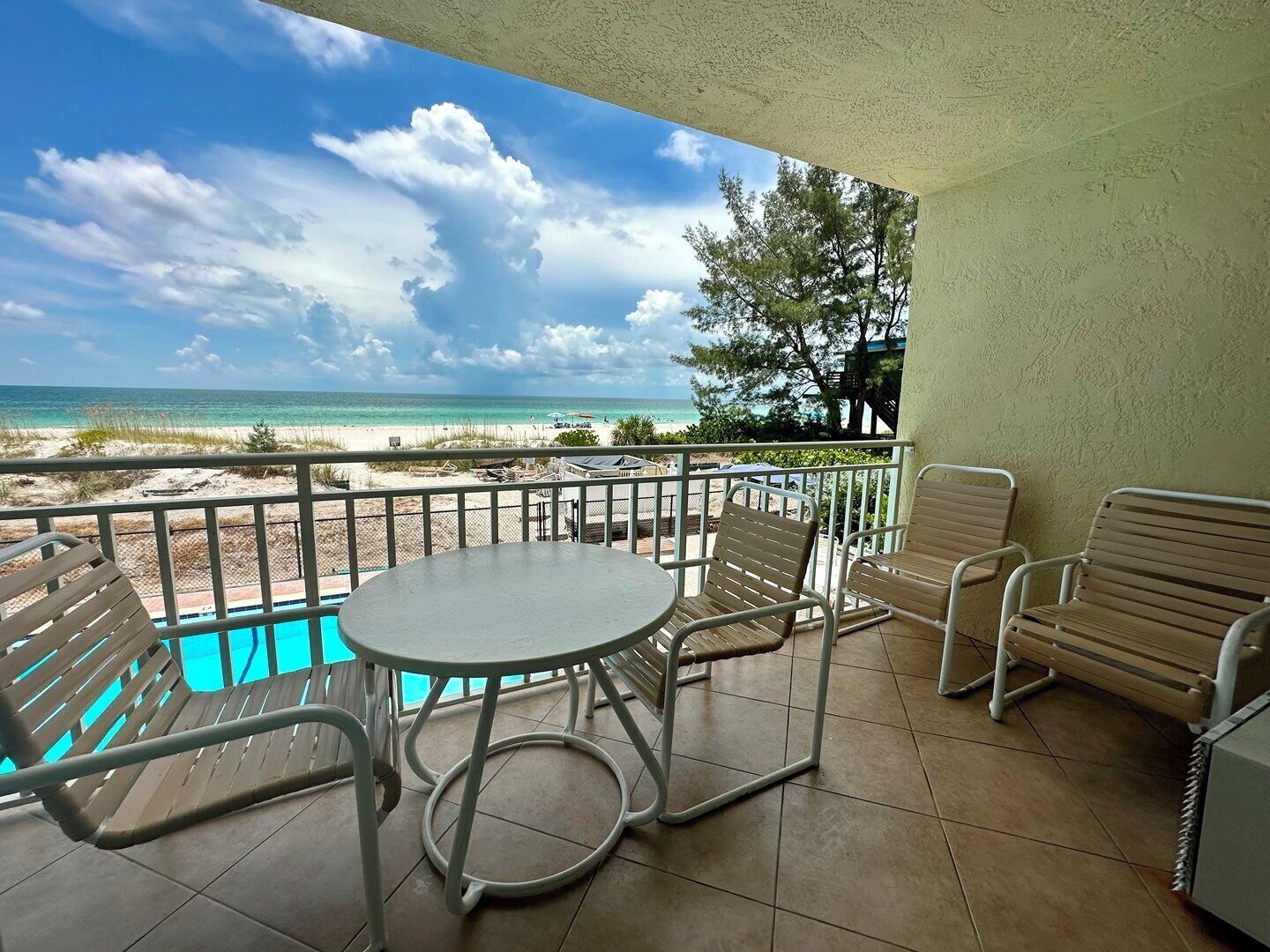 Ein Balkon mit Pool, Stühlen und Blick auf Strand und Meer.