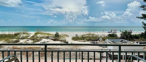 A balcony with a view of a beach and ocean.