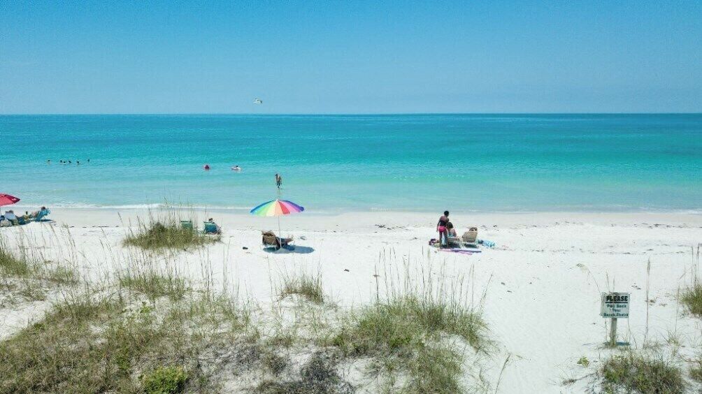 Une plage de sable blanc, quelques parasols et un panneau.