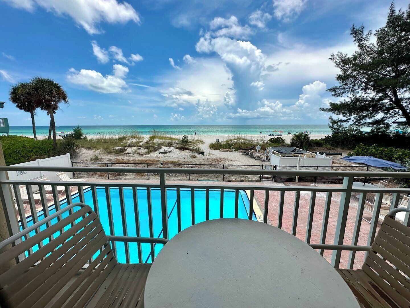 A pool area with a view of the beach and ocean.