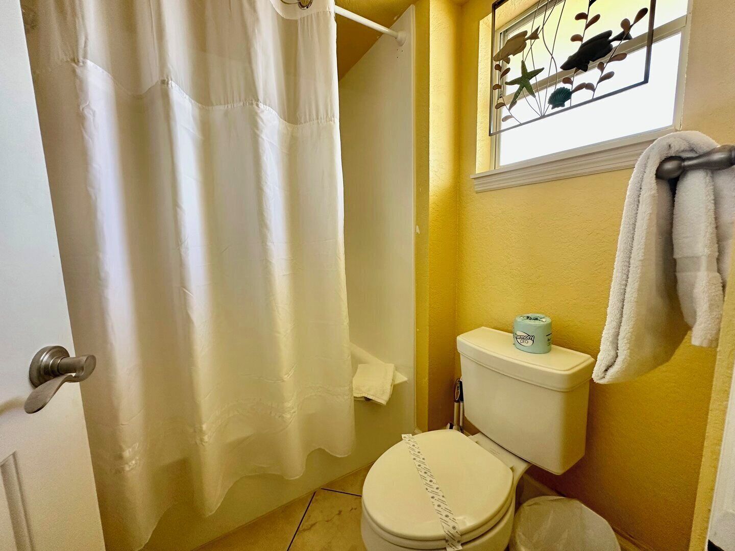 Une salle de bain équipée de toilettes, d’un rideau de douche et d’un porte-serviettes.
