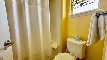 Une salle de bain équipée de toilettes, d’un rideau de douche et d’un porte-serviettes.