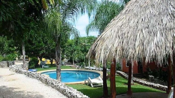 A pool area with a thatched roof structure, surrounded by stone walls and greenery. - Pueblo del Mar 4☙Monkeys & Birds will make your mornings special❧ (Tamarindo)