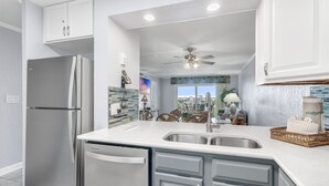 A modern kitchen with a refrigerator, dishwasher, and a large sink.