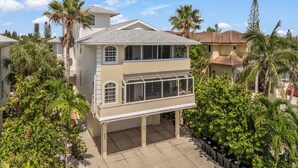A two-story house with a covered patio, surrounded by palm trees and other greenery. - Steps to Beach. Shared Pool Pet/Family Friendly. Parking Incl. (Siesta Key)