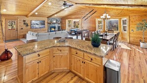 A spacious kitchen with wooden cabinets, a granite countertop, and a central island. - Golden Oaks by Destination Big Bear :Luxury Log Cabin w/ Peaceful Setting in High End Neighborhood! Foosball Table/Arcade Game! Gourmet Kitchen! Master Suite w/Private Bathroom! Garage Parking! Propane BBQ! (Big Bear Lake)