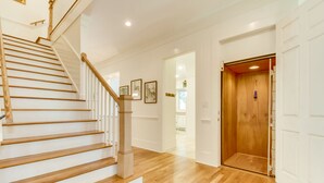 A staircase with wooden steps and a handrail, leading to an elevator.