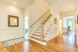 Staircase leads to an upper level, with a dining area visible in the background.