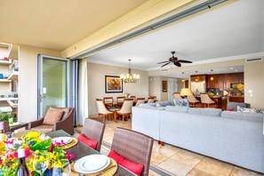 Ein modernes Wohnzimmer mit einer Couch, einem Esstisch und Stühlen, einer Küchenzeile und einem Balkon mit Sitzgelegenheit.