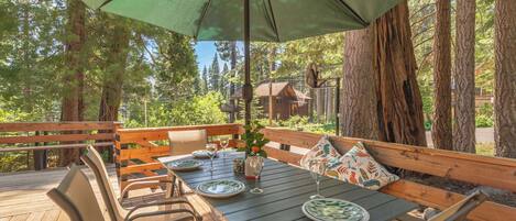 An outdoor dining area with a table set for four, surrounded by wooden benches and chairs.