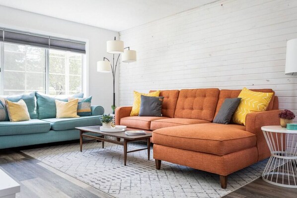 A living room with a sectional sofa, a smaller sofa, a coffee table, and a floor lamp.