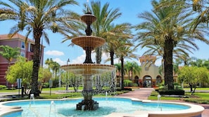A multi-tiered fountain surrounded by palm trees and a building with arched windows in the background. - Spacious 3-BR Townhouse Near Theme Parks Orlando (Orlando)