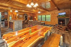Cozy cabin with a large dining table, comfortable seating area, and stone fireplace.